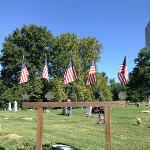 Small flags are lined up on a railing in front of the cemetery