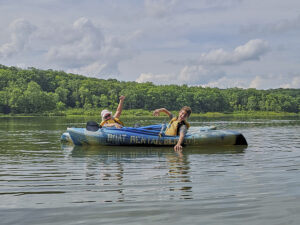An older woman and preteen boy are in their life vests in a blue rental kayaks. 
